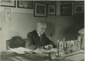Lietuvių Vytauto Didžiojo gimnazijos direktorius, matematikos mokytojas Marcelinas Šikšnys darbo kabinete. Vilnius. Apie 1934 m. Lietuvos nacionalinis dailės muziejus. Naudojimo teisės: PD. Nuotrauka iš Europeanos