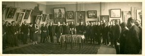 Pavasarinės Lietuvos dailės parodos atidarymas Lietuvos universiteto rūmų salėje. 1926 m. Parodos atidaryme dalyvauja: aštunta – operos solistė Adelė Galaunienė, Vytauto bažnyčios rektorius Juozas Tumas-Vaižgantas, dailininkas Kajetonas Sklėrius, LR Prezidentas Aleksandras Stulginskis. Iš dešinės: septintas – Petras Kalpokas, Antanas Žmuidzinavičius, tryliktas – Mykolas Riomeris. 1926 m. KMM F 11. Kauno miesto muziejus. Naudojimo teisės: CC BY-NC-ND. Nuotrauka iš LIMIS