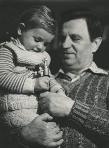 Ona Pajedaitė. Iš rinkinio „Poetai“. Liaudies poetas Justinas Marcinkevičius su anūku Justuku. 1983 m. Lietuvos fotomenininkų sąjunga. Naudojimo teisės: CC BY-NC-ND. Nuotrauka iš Europeanos