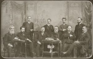 Lietuvių mokslo draugijos komitetas. Sėdi, iš kairės: Juozas Kairiūkštis, Antanas Smetona, Augustas Niemi, Jonas Basanavičius, Antanas Vileišis ir Jonas Vileišis. Stovi, iš kairės: Juozas Balčikonis, Zigmas Žemaitis, Mykolas Biržiška, Jurgis Šlapelis. 1911–1912 m. Marijos ir Jurgio Šlapelių namas-muziejus. Naudojimo teisės: PD. Nuotrauka iš Europeanos