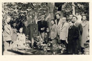 Rašytojai ir artimieji Rasų kapinėse, minint poeto Liudo Giros 10-ąsias mirties metines. Prie L. Giros kapo stovi iš kairės: Teofilis Tilvytis, trečia – Danutė Sirijos Giraitė, ketvirta – Bronislava Girienė, penktas – Vytautas Sirijos Gira, šeštas – Algirdas Sirijos Gira, septinta – Janina Sirijos Girienė, aštuntas – Vacys Reimeris, devintas – Antanas Venclova, dešimtas – Jokūbas Skliutauskas; antroje eilėje iš dešinės: Mykolas Sluckis, Jonas Šimkus, Eugenijus Matuzevičius. 1956 m. MLLM F 200. Maironio lietuvių literatūros muziejus. Naudojimo teisės: PD. Nuotrauka iš LIMIS