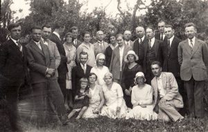 Panevėžio mokytojų seminarijos 1923 m. laidos absolventų ir mokytojų susitikimo dalyviai gamtoje. Priekyje iš dešinės aštuntas sėdi kalbininkas Juozas Balčikonis. Vieta nežinoma. XX a. 4 deš. Panevėžio kraštotyros muziejus. Naudojimo teisės: PD. Nuotrauka iš Europeanos