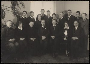 Prof. Mykolo Römerio gimimo dienos paminėjimas. I eilėje iš kairės: 3-as kun. Žilinskas, 4-as prof. M. Römeris. II eilėje iš kairės: 3-as Banaitis, 5-as L. Kazokas. 1930–1932 m. ČDM M 1-56-6/12. Nacionalinis M. K. Čiurlionio dailės muziejus. Naudojimo teisės: CC BY-NC. Nuotrauka iš LIMIS