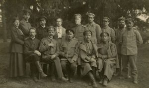 Jurgis Šlapelis tarp kariškių Pirmojo pasaulinio karo metu. Sėdi antras iš dešinės. 1918 m. Marijos ir Jurgio Šlapelių namas-muziejus. Naudojimo teisės: PD. Nuotrauka iš Europeanos