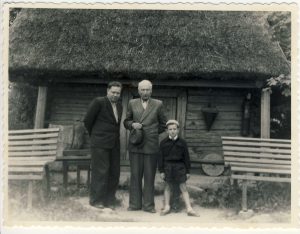 Rašytojas Antanas Vienuolis-Žukauskas (viduryje) su lankytojais prie poeto Antano Baranausko klėtelės Anykščiuose. XX a. 6 deš. I p. VŽM F 523. A. Baranausko ir A. Vienuolio-Žukausko memorialinis muziejus. Naudojimo teisės: PD. Nuotrauka iš LIMIS