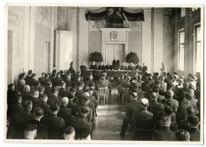 Vilniaus įgulos kariškiai Vasario 16-osios minėjime. Prezidiume sėdi iš kairės: brig. gen. Antanas Gustaitis, Vilniaus burmistras Konstantinas Stašys, Susisiekimo ministras Jonas Masiliūnas, Kazys Bizauskas, stovėdamas kalba Antanas Merkys, sėdi: brig. gen. Kazys Musteikis, div. gen. Vincas Vitkauskas, brig. gen. Jonas Černius, brig. gen. Juozas Barzda-Bradauskas. 1940 m. LAM VF 10758. Lietuvos aviacijos muziejus. Naudojimo teisės: CC BY-NC-ND. Nuotrauka iš LIMIS