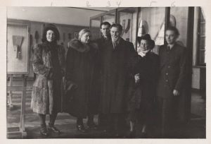 Dailininkai M. K. Čiurlionio dailės muziejaus ekspozicijos salėje. Domicelė Tarabildienė stovi antra iš dešinės. 1951 m. Nacionalinis M. K. Čiurlionio dailės muziejus. Naudojimo teisės: CC BY-NC-ND. Nuotrauka iš Europeanos