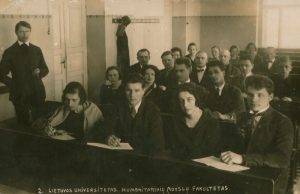 Rašytojo, prof. B. Sruogos paskaita Lietuvos universitete. Balys Sruoga stovi kairėje. Trečioje eilėje sėdi (iš kairės) poetas Jonas Graičiūnas, aktorius, dramaturgas Kazys Inčiūra, rašytojas Antanas Venclova ir kiti humanitarinių mokslų fakulteto studentai. Apie 1925–1926 m. Maironio lietuvių literatūros muziejus. Naudojimo teisės: PD. Nuotrauka iš Europeanos