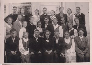 J. Strielkūnas (pirmoje eilėje, trečias iš dešinės) su klasės draugais klasės išleistuvėse. 1957 m. MLLM F3 24313. Maironio lietuvių literatūros muziejus. Naudojimo teisės: PD. Nuotrauka iš LIMIS