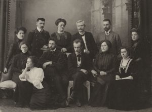 Leonhard von Wirschikowski. Lietuvių dailės parodos komitetas Rygoje. Pirmoje eilėje sėdi (iš kairės į dešinę): dantų gydytoja Marijona Putvinskaitė-Žmuidzinavičienė, dailininkas Antanas Žmuidzinavičius, skulptorius Petras Rimša; antroje eilėje stovi Kazimieras Gabrėnas (1878–1951; antras iš kairės), pedagogas bei rašytojas Pranas Mašiotas (1863–1940; ketvirtas iš kairės), Emilija Vileišienė (trečia iš kairės). 1910 m. balandis. ČDM Ta 1023. Nacionalinis M. K. Čiurlionio dailės muziejus. Naudojimo teisės: CC BY-NC. Nuotrauka iš LIMIS